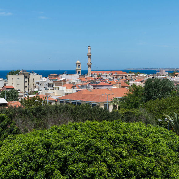 Θέα πάνω από τις κορυφές των δέντρων στις στέγες της Παλιάς Πόλης, το καμπαναριό, τον μιναρέ και τη θάλασσα