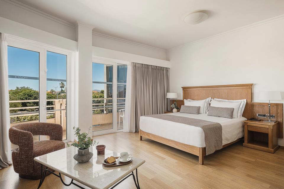 Junior Suite with king size bed and seating corner beside floor-to-ceiling windows facing the sea