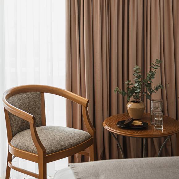 Cosy corner with wooden armchair, round table, welcome treat and eucalyptus by the window