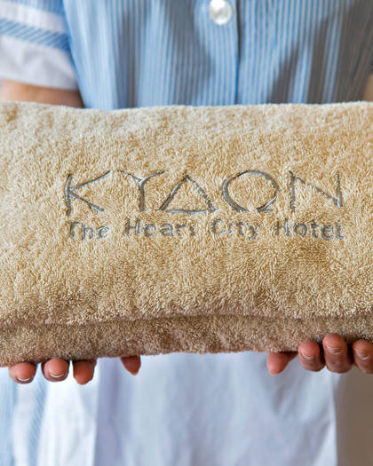 Staff member holding a folded embroidered towel, fresh from housekeeping