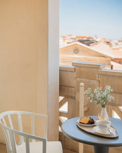 Private balcony table set with breakfast and fresh flowers, overlooking the Old Town rooftops