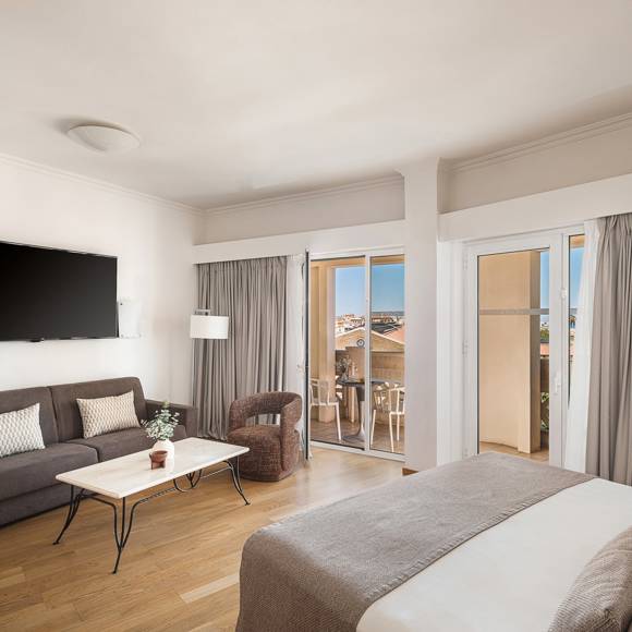 Open plan Junior Suite with sofa bed area, wall-mounted TV and balcony overlooking the Old Town